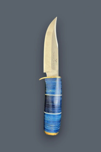 Diagonal view of the Blazefury Hunter stainless steel hunting knife, highlighting the blue wood handle and polished brass bolster assembly.