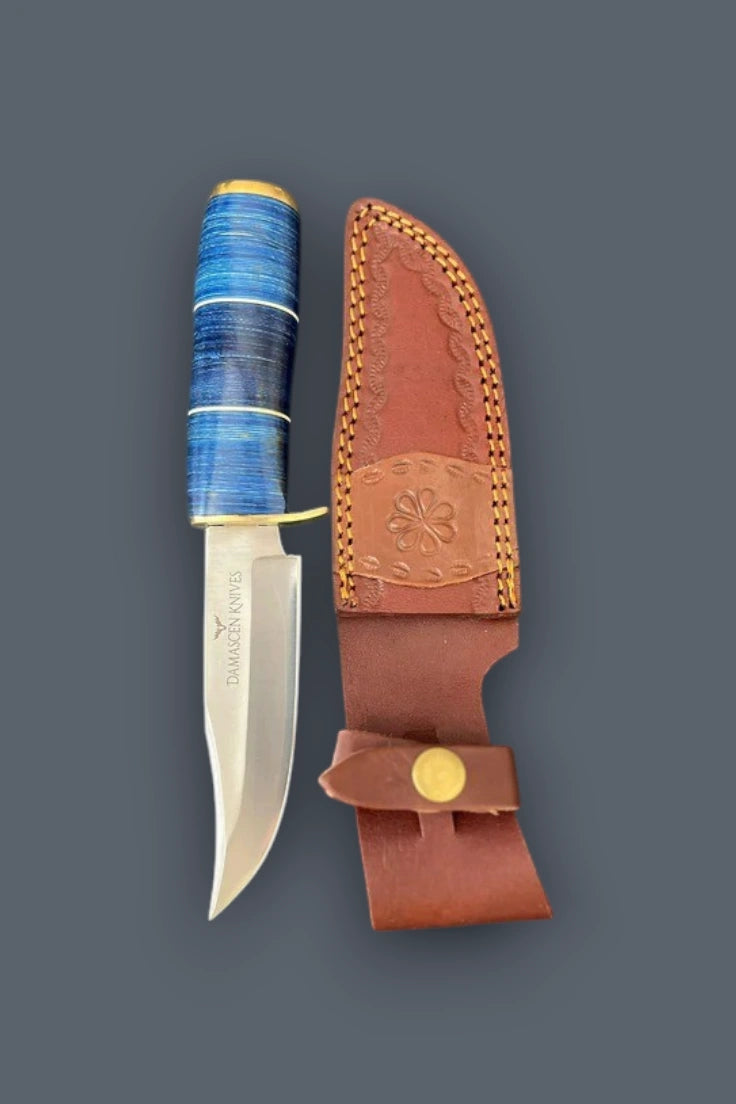 Vertical flat lay of the Blazefury Hunter stainless steel hunting knife with a blue wood handle, alongside its stamped cowhide leather sheath.