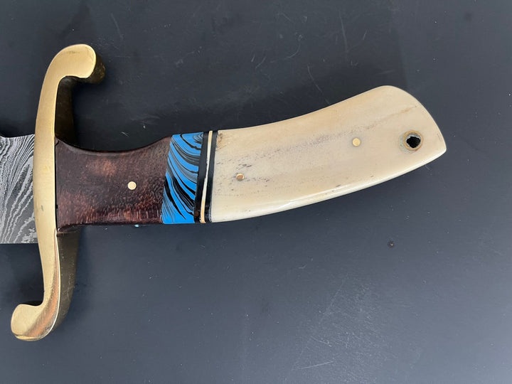 Close-up of polished bone handle with blue accent and brass guard