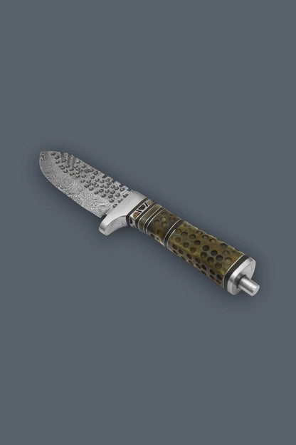 Diagonal flat lay of a Damascen Knives fixed blade hunting knife, showcasing the heavily textured Damascus steel blade and dimpled cylindrical bone handle.
