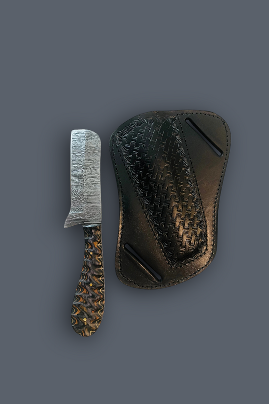 A small damascus razor blade knife with a textured silver blade and a patterned brown handle, shown next to a dark brown woven leather sheath on a solid dark gray background.