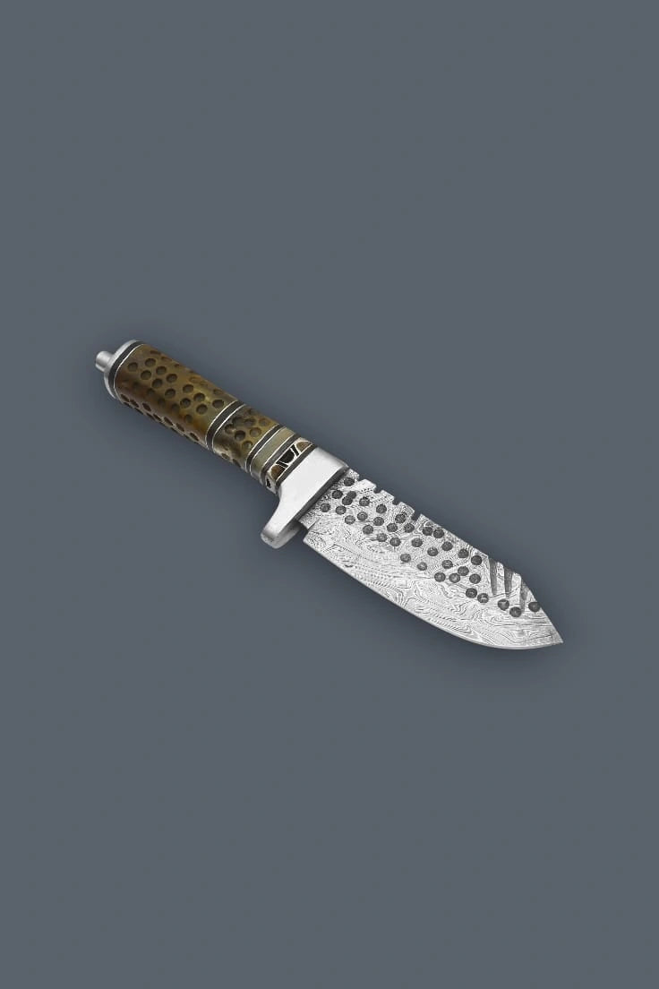 Downward diagonal flat lay displaying the reverse side of the Damascen Knives hunting knife, highlighting the hammered blade texture and metal handle spacers.