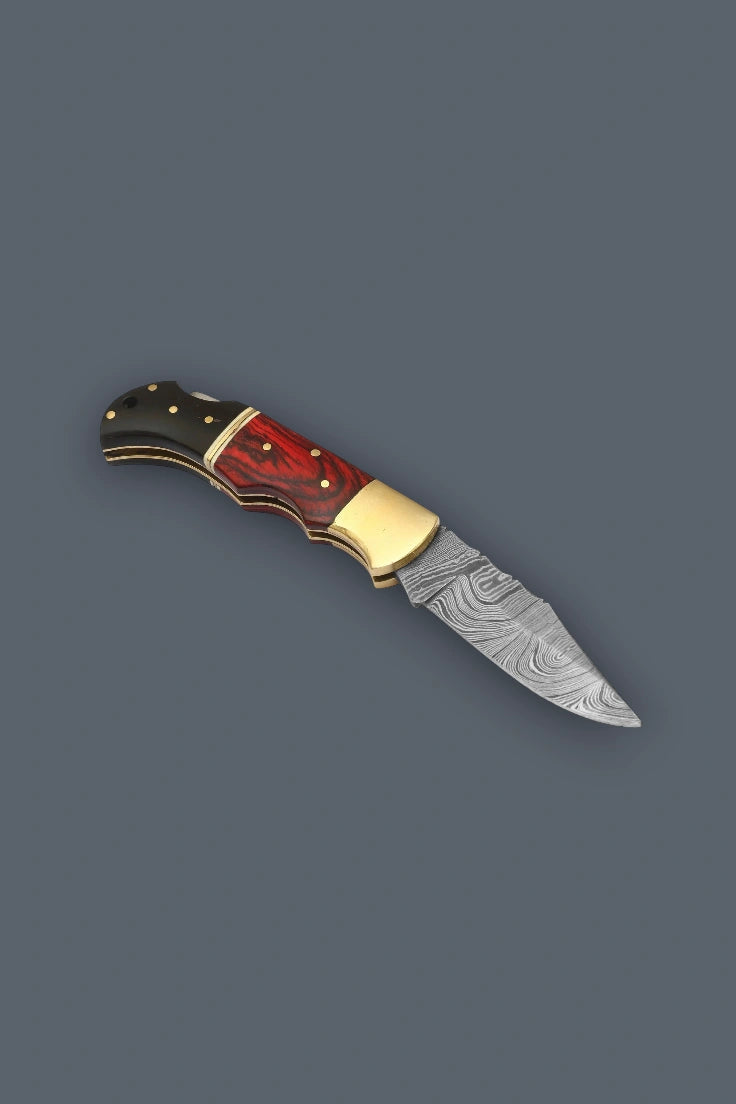 Full side profile of the open Pioneer Pocket Damascus folding knife showcasing the blade pattern, brass bolster, and multicolor wood handle.