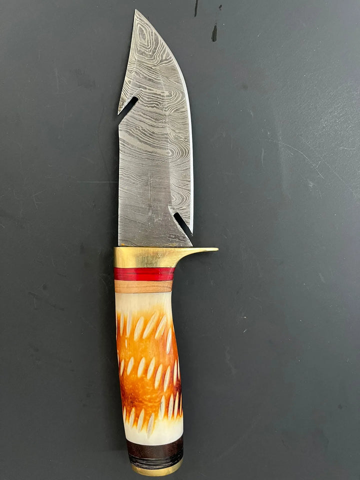 Hand-forged Damascus steel hunting knife with burned wood horn handle on dark background.