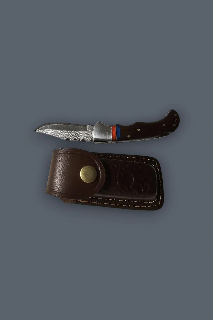 Horizontal flat lay of the fully open The Gentry Knife positioned directly above its closed brown tooled leather sheath.