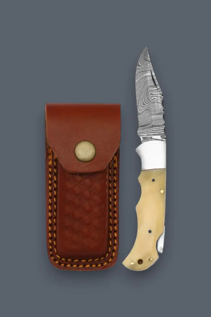Opened lockback Damascus folding knife displayed next to its handcrafted leather sheath.