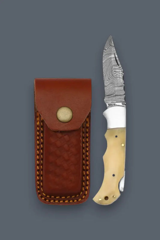 Opened lockback Damascus folding knife displayed next to its handcrafted leather sheath.