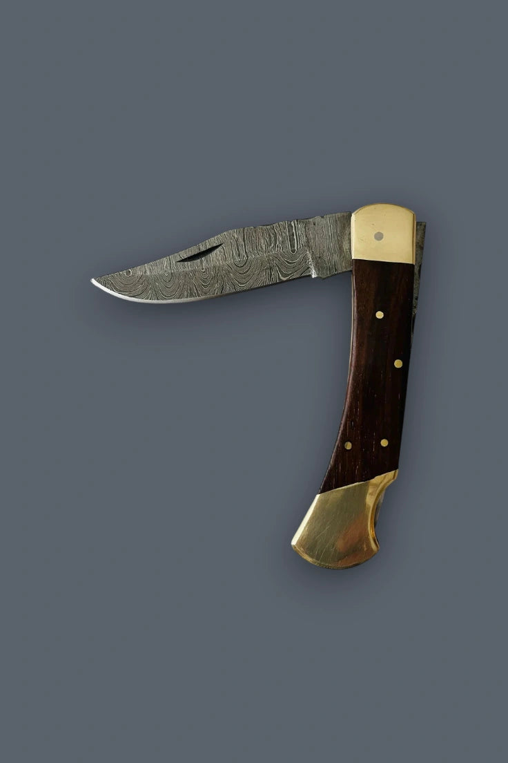 Flat lay of the partially open Old World Edge Damascus folding knife at a 90-degree angle, showcasing the wood handle and double brass bolsters.