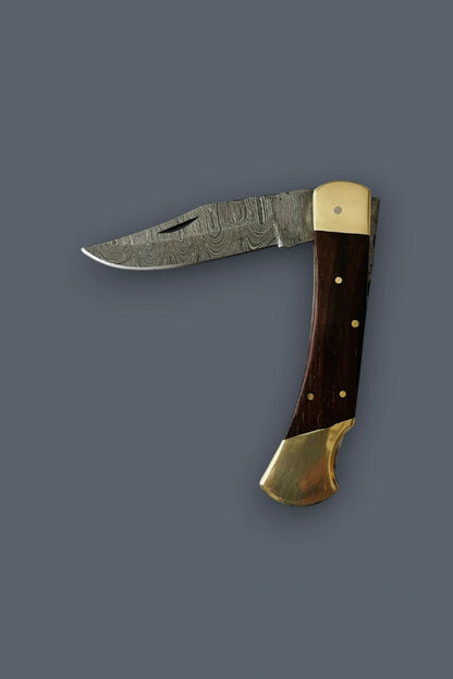 Flat lay of the partially open Old World Edge Damascus folding knife at a 90-degree angle, showcasing the wood handle and double brass bolsters.