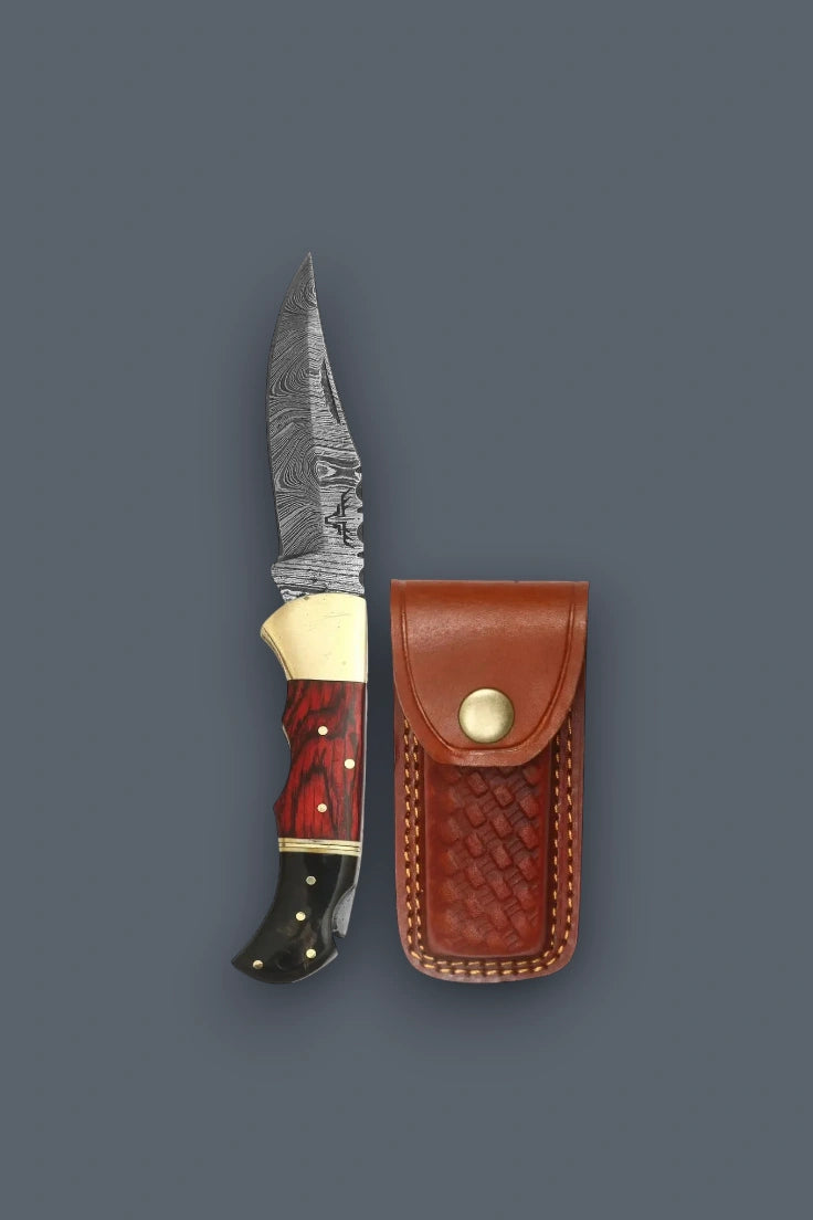 Vertical flat lay of the open Pioneer Pocket Damascus folding knife positioned alongside its closed brown basketweave leather sheath.