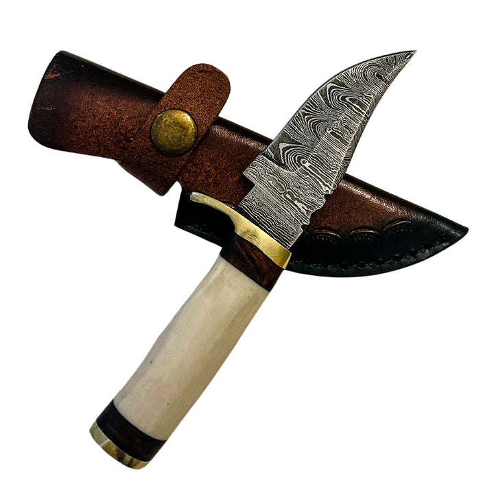 Angled view of Damascus skinning knife with bone handle and brass guard