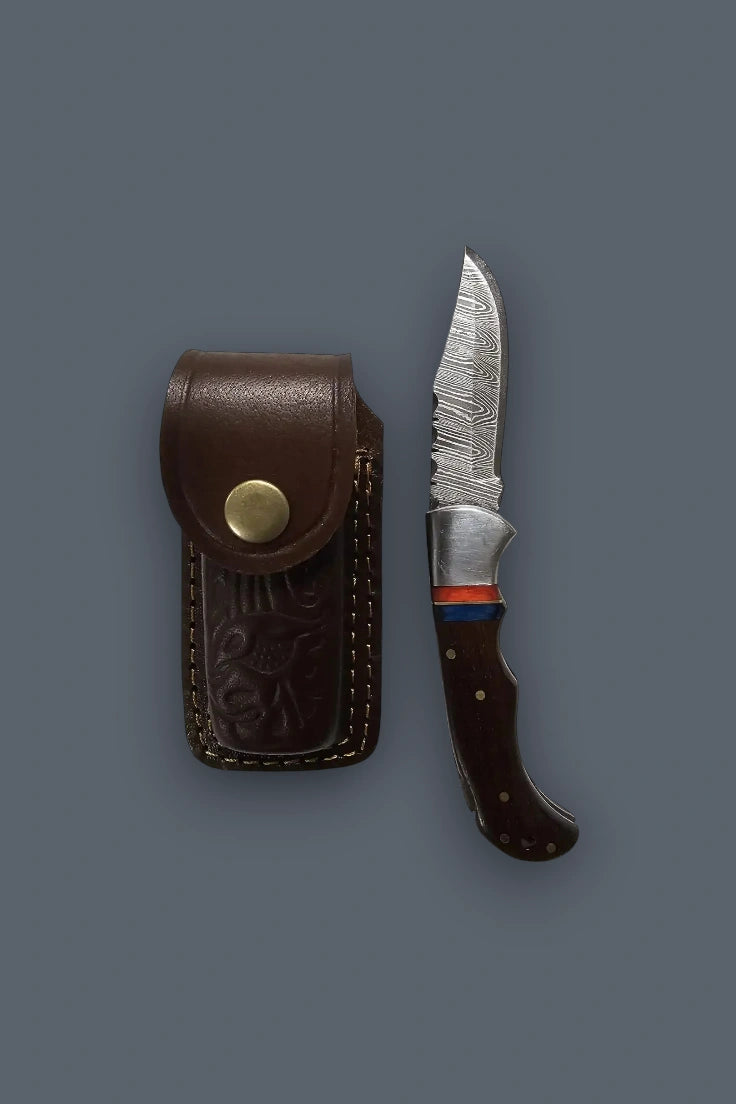 Vertical flat lay of the fully open The Gentry Knife positioned alongside its closed brown tooled leather sheath.