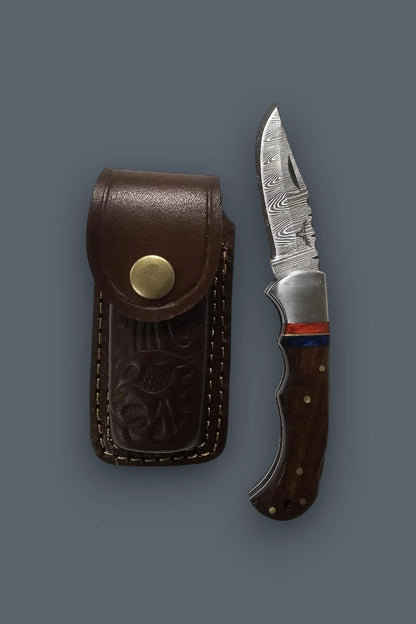 Vertical display of the fully open The Gentry Knife paired with its custom brown tooled leather sheath, highlighting the complete everyday carry set.