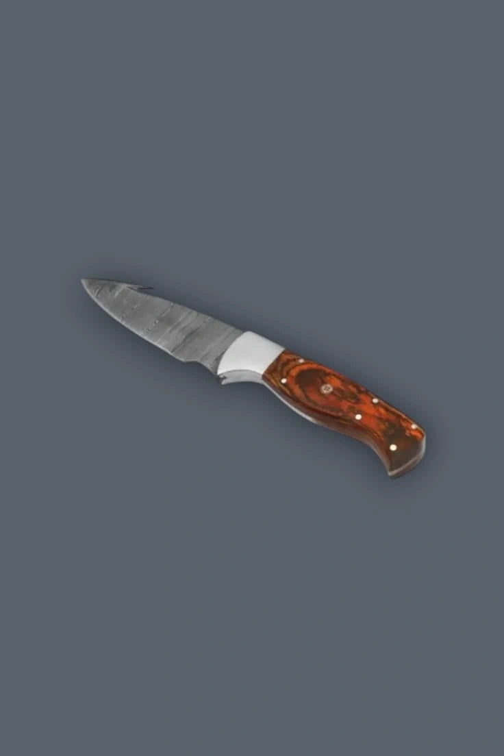 Upward diagonal flat lay of a fixed blade Damascus hunting knife, highlighting the curved pommel of the multi-tone wood handle and the spine gut hook.