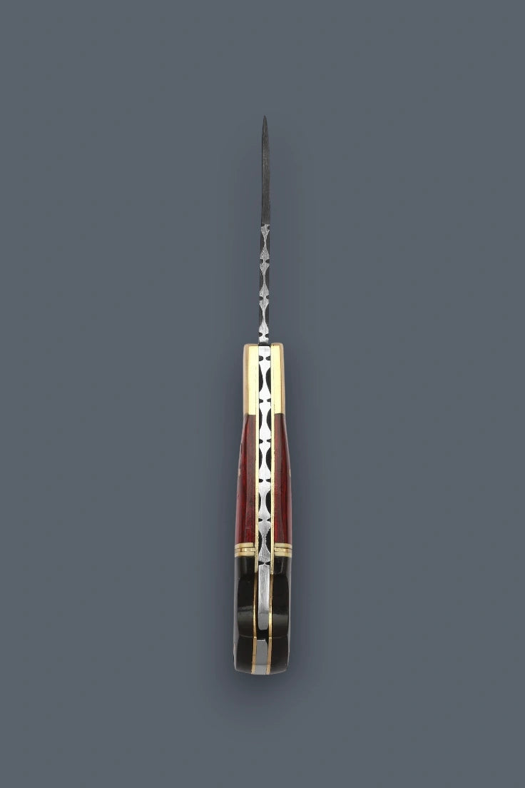 A folding pocket knife with a silver-toned metal blade and handle, featuring a reddish-brown and gold geometric inlay pattern, shown against a solid dark gray background.