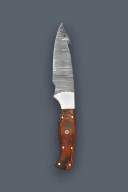 Vertical top-down flat lay of a Damascus steel fixed blade hunting knife featuring a prominent spine gut hook and contoured multi-tone wood handle.